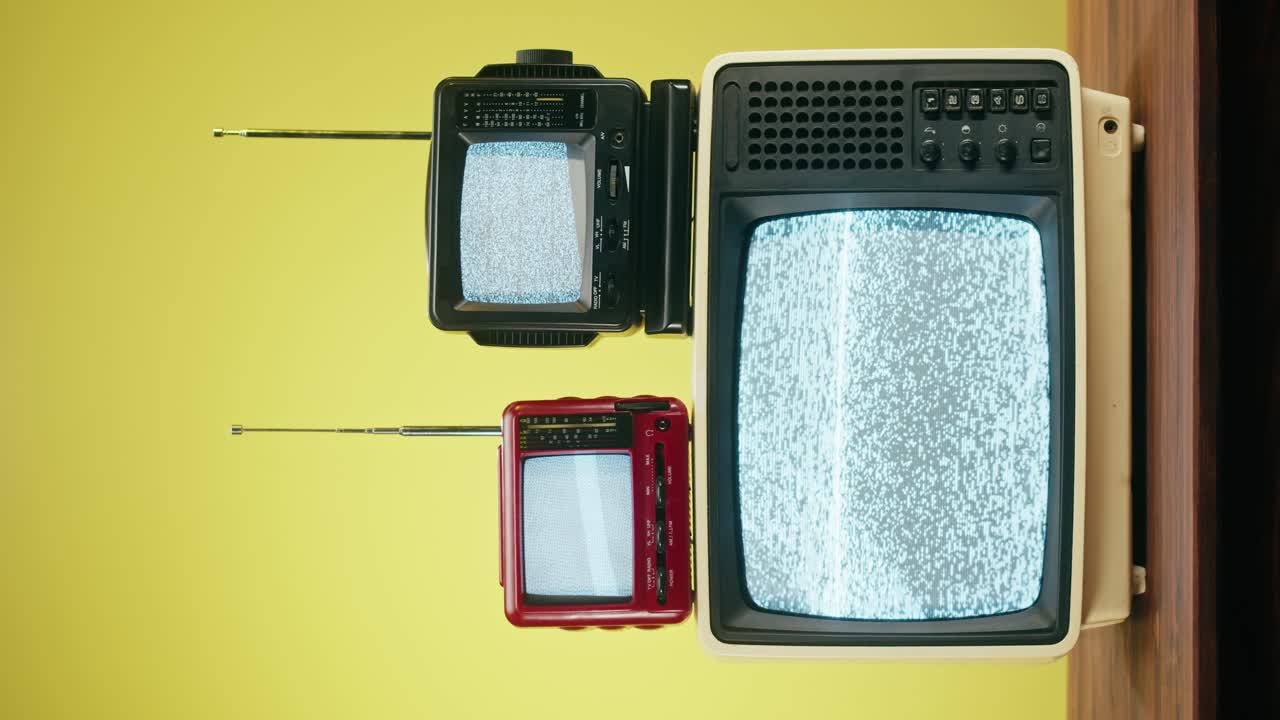 Three vintage television sets with static on the screens