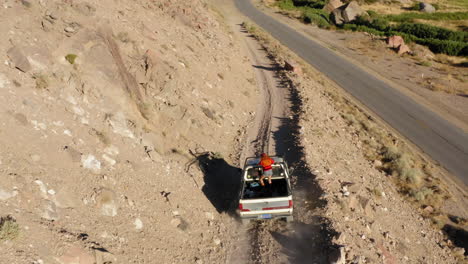 Aerial-footage-of-a-car-driving-on-a-mountain-road-and-going-down-to-a-highway-in-Bishop,-CA