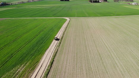 tractor driving countryside road among crops field in poland