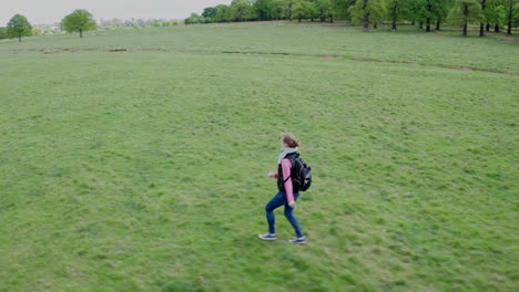 aerial view of a woman running with a backpack on for a short distance, then stopping to look behind