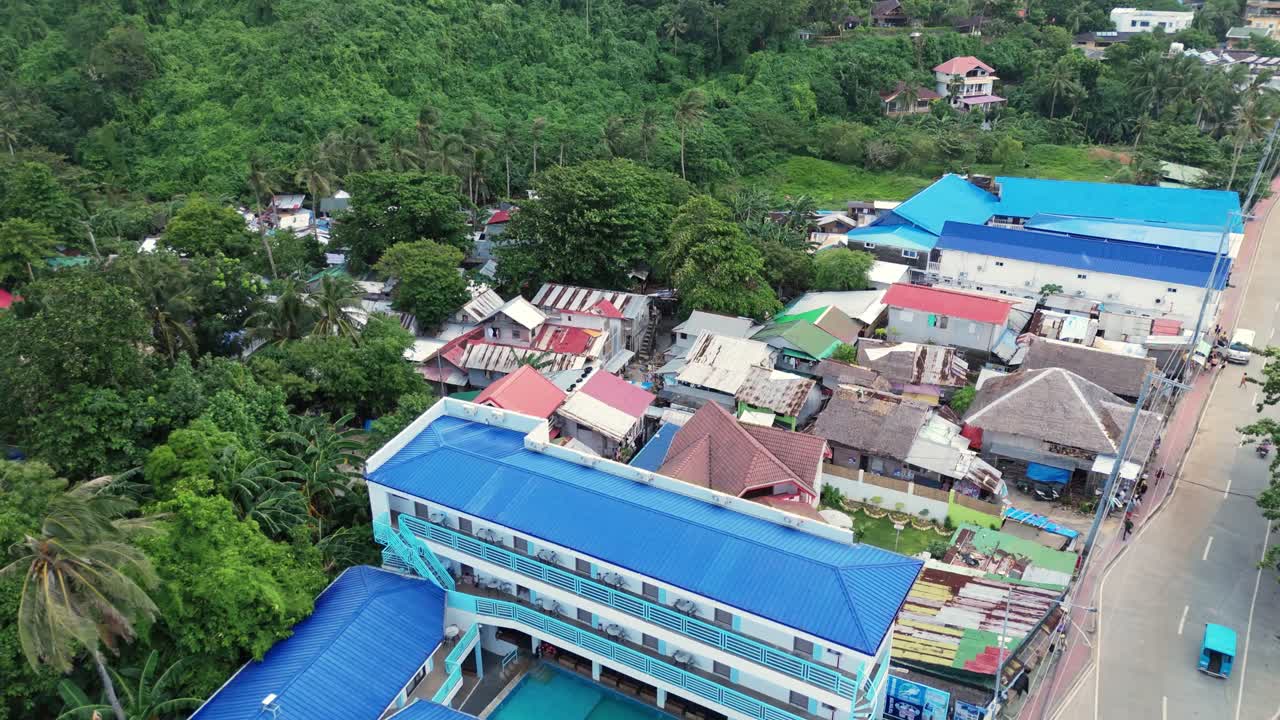 Rainy aerial view over Boracay village, Philippines, with colorful rooftops, palm trees, and a coastal road. Great for travel, weather, and cinematic location footage