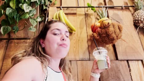 woman vlogging and drinking a smoothie in a rustic cafe