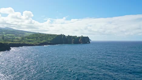 coastal cliffs and lush green landscape meet the blue ocean under a sunny sky