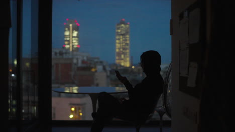 person using smartphone at night with city view