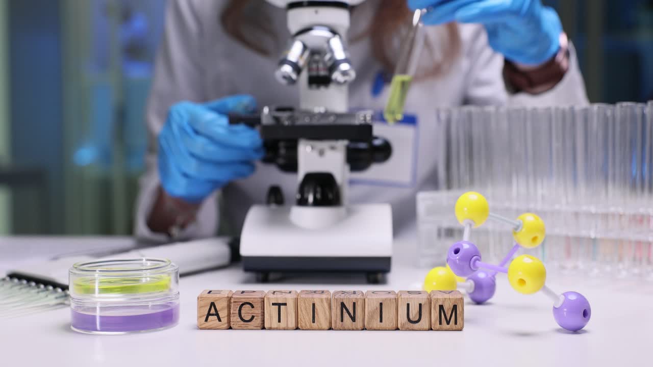 Actinium Word Blocks on Lab Table with Scientist and Microscope