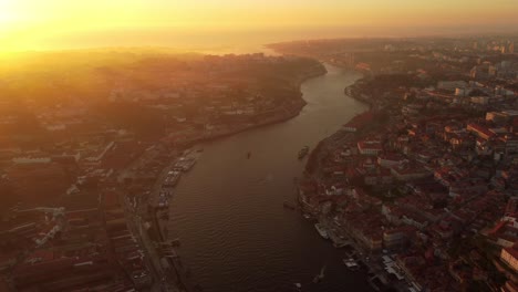 Vista-Panorámica-Aérea-De-La-Puesta-De-Sol-De-La-Ciudad-De-Porto-Al-Norte-De-Portugal,-Drones-Vuelan-Sobre-El-Río-Douro-Durante-La-Hora-Dorada