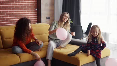 Mother-and-her-sister-are-playing-with-balloons-with-blondy-small-girl