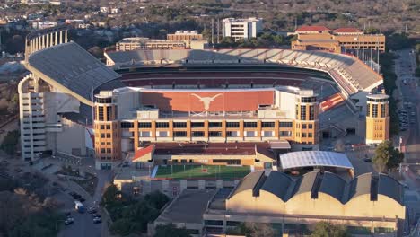 A wide drone shot at sunset panning right and revealing the Longhorns logo on the empty Darrell K Royal Texas Memorial Stadium at the University of Texas (UT) in Austin