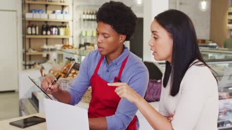 video of diverse female owner and male waiter working with laptop at cafe shop