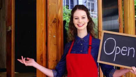 smiling waitresses holding open sign board