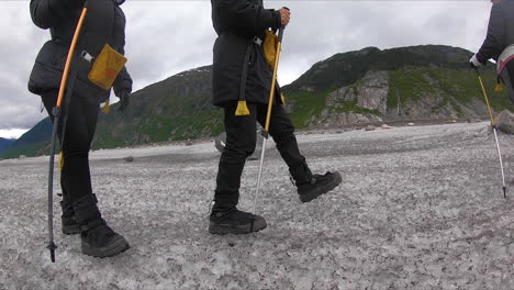 los excursionistas caminan en cámara lenta a lo largo de la parte superior de un glaciar de alaska