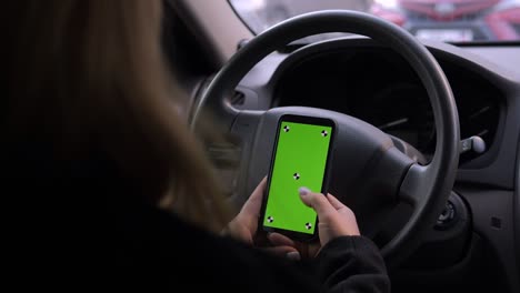 una mujer está conduciendo un coche con un teléfono en sus manos, una llave de croma en la pantalla.