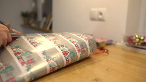 woman's hands wrapping christmas or other holiday handmade present in paper with red ribbon