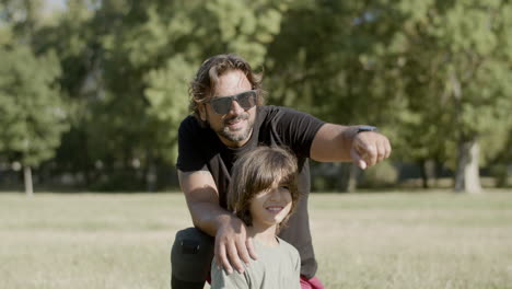 father with disability sitting with son on lawn in park