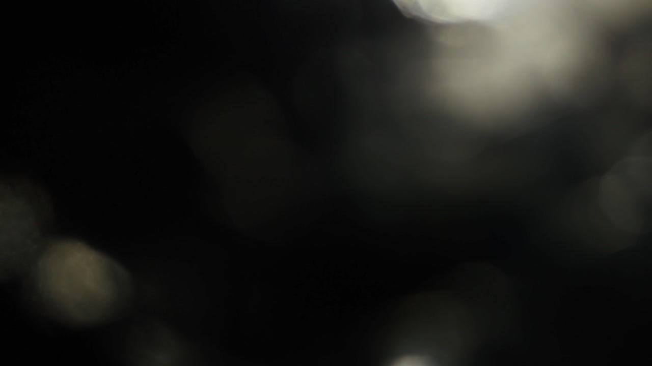 Flimrende gyldne bokeh-lyslækager på mørk baggrund