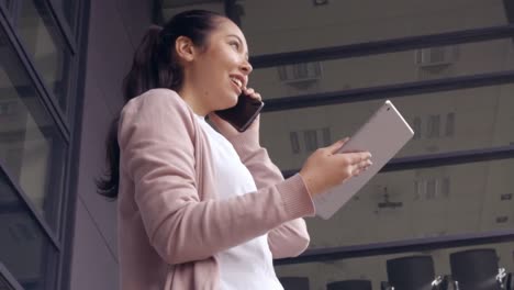 asian businesswoman using her phone and tablet outside