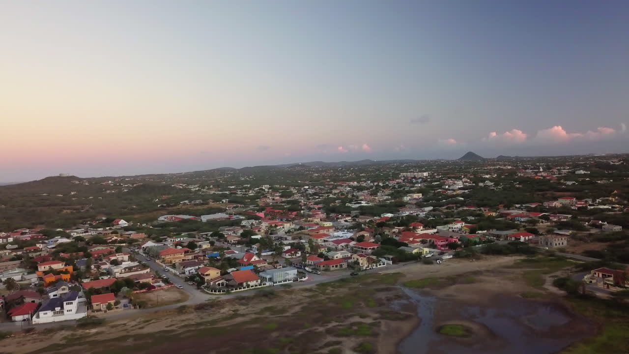 Quartieri ad Aruba con Hooiberg e il Mar dei Caraibi sullo sfondo al tramonto