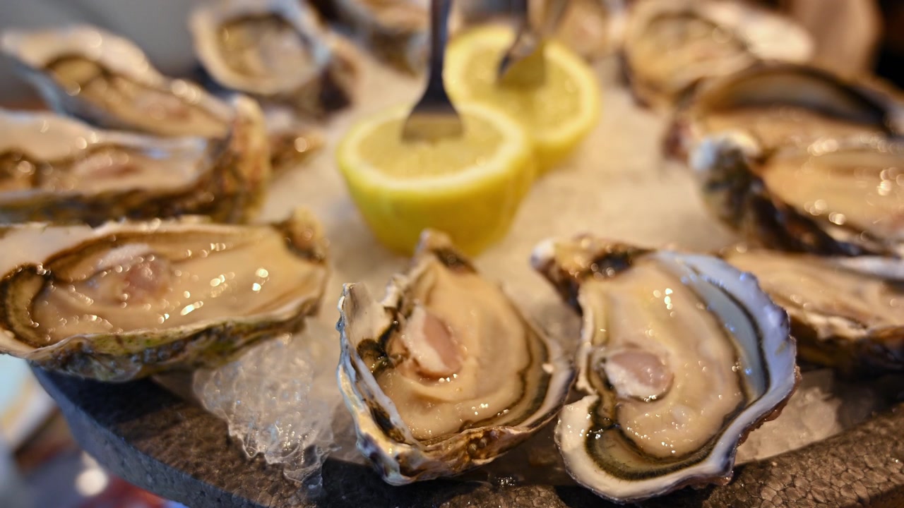 Fresh oysters displayed on crushed ice with sliced lemons in a seafood restaurant setting