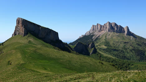 rolling green hills of caucasus mountain range with sheer cliff on blue day