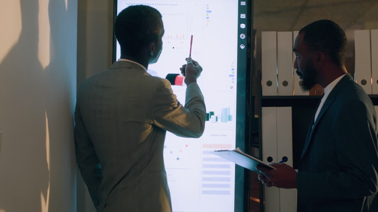 Businessmen discussing data on a screen in an office