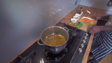 caribbean chef preparing a sauce with mixed vegetables in pot