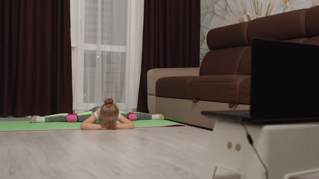 ребенок девочка занимается гимнастикой фитнес растягивает шнур дома, видео-учебник дистанционное обучение