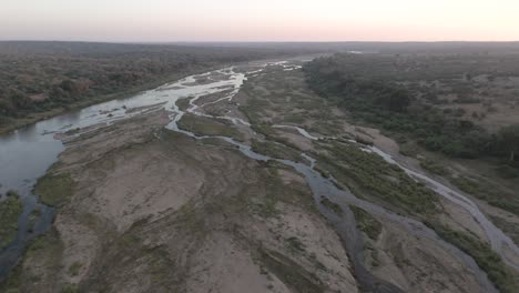 Meandering-water-braids-across-dry-sandy-dirt-on-banks-of-seasonal-crocodile-river-in-KNP