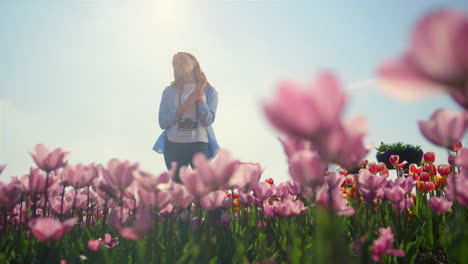 young woman in casual clothes standing in dreams in flower garden in sunshine.