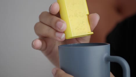 person adding sugar to their coffee