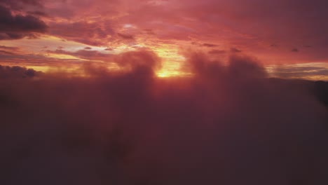 bright red sun behind misty clouds in sky at sunset, 4k drone