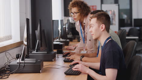 group of college students with tutor studying computer design sitting at monitors in classroom