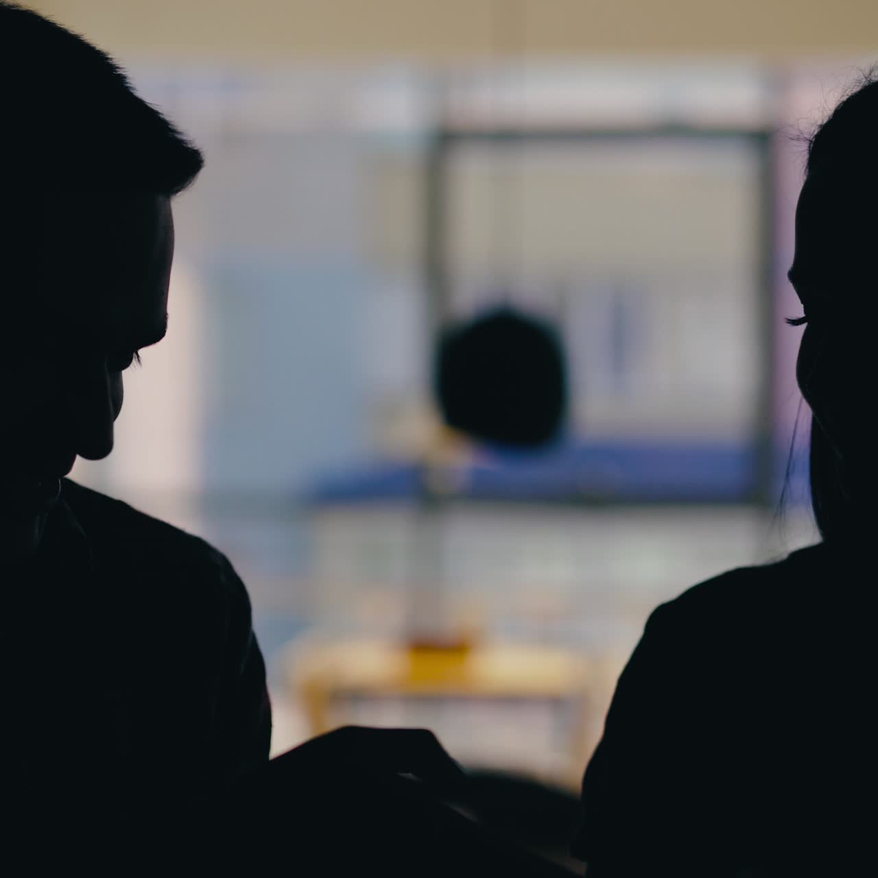 A man and a woman are drinking drinks from tubules on a blurred background in a cafe. Love story. Silhouette of lovers