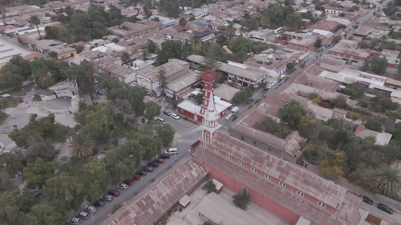 Wide drone shot around the town of Vicuña near Coquimbo in Chile South America with the main square and red tower Torre Bauer visible on a grey day LOG