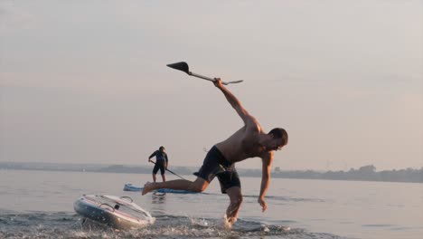 man falling from a board into the sea during sunset