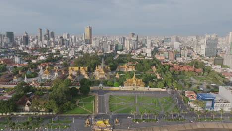 aerial video of phnom penh shows the royal palace and surrounding greenery in full sunlight, with the city rising behind it