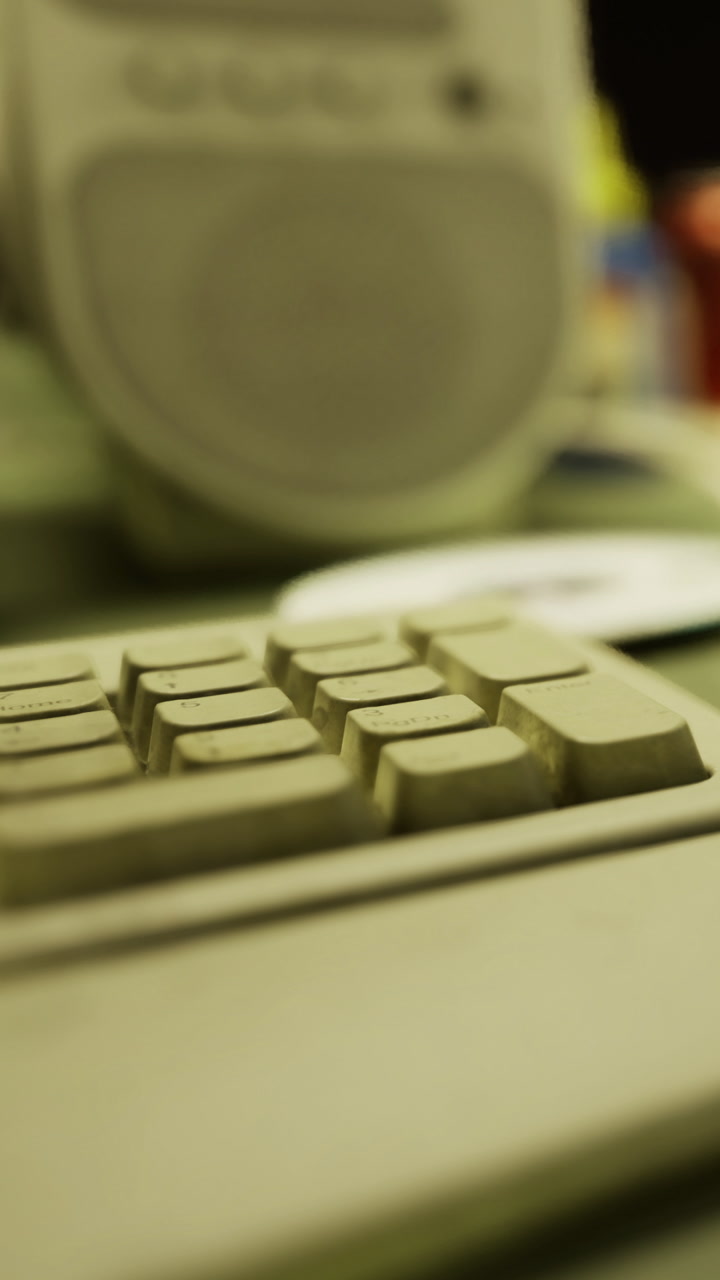 Close view of a computer keyboard with a speaker and a cd in the background
