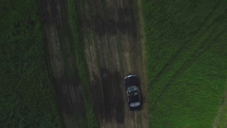 black car on a dirt road in a field