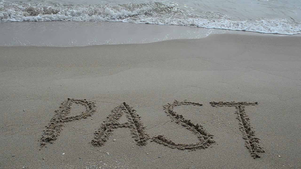 The inscription "PAST" on a wet sand seacoast. Shooting on the beach