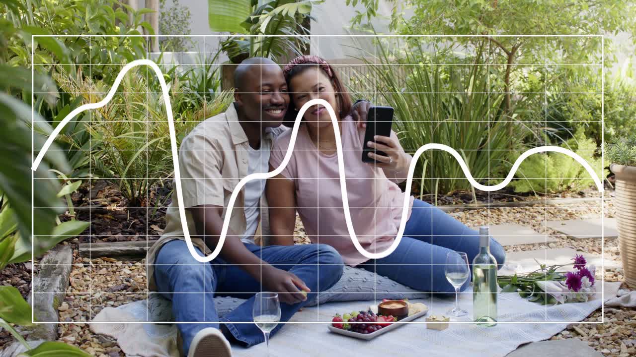 Woman raising phone, taking selfies while man snuggling on blanket, waveform guiding social media