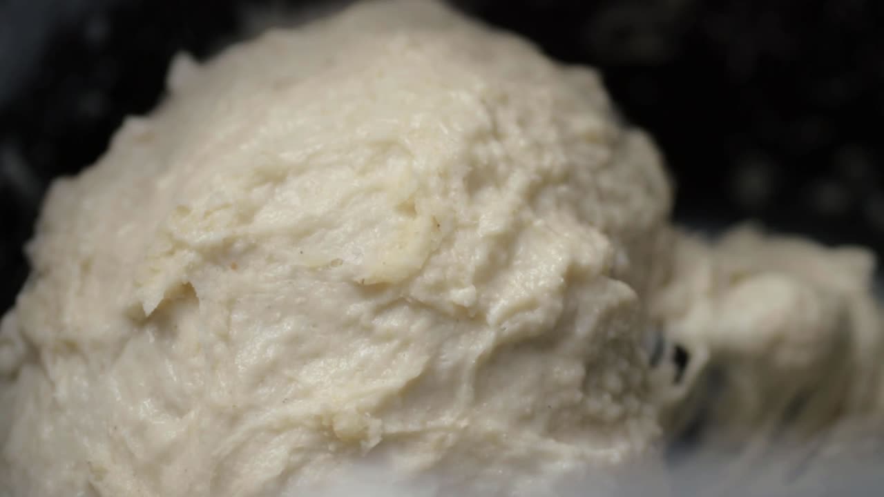 Bread machine mixing dough in pan macro shot