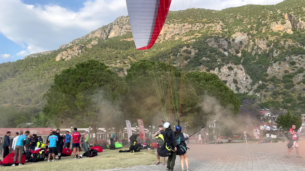 Turkey,Fethiye,Oludeniz, Paragliders are landing one by one to the boardwalk between people. Paragliding parade at the beach at Fethiye