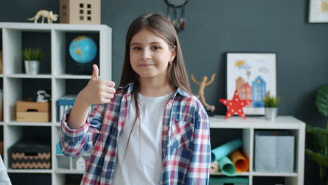 girl giving a thumbs up in a room