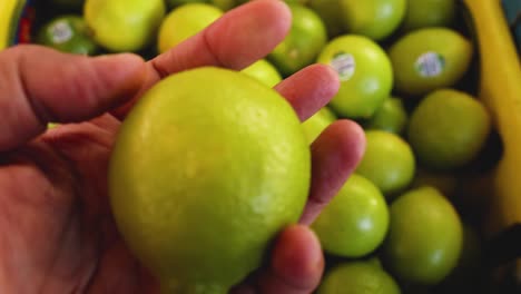 hand picking limes from a market display