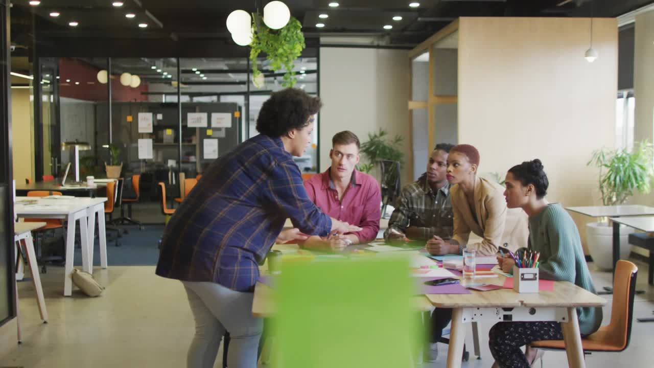 Mujer repartiendo diagramas de colores con prompts de medios que aparecen alrededor de un equipo de negocios colaborando