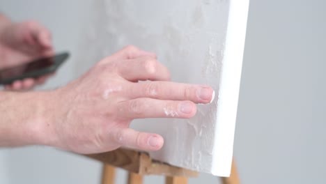 the artist applies a plaster base on a white canvas the artist applies a plaster base on a white canvas the artist works in his modern studio modern abstract art