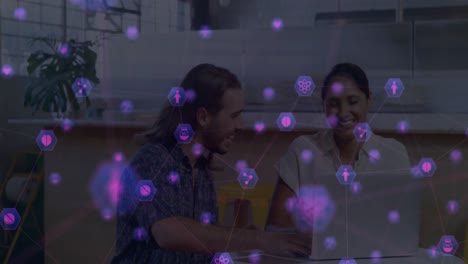 animación de una red de iconos digitales sobre un hombre y una mujer diversos discutiendo en una computadora portátil en la oficina.