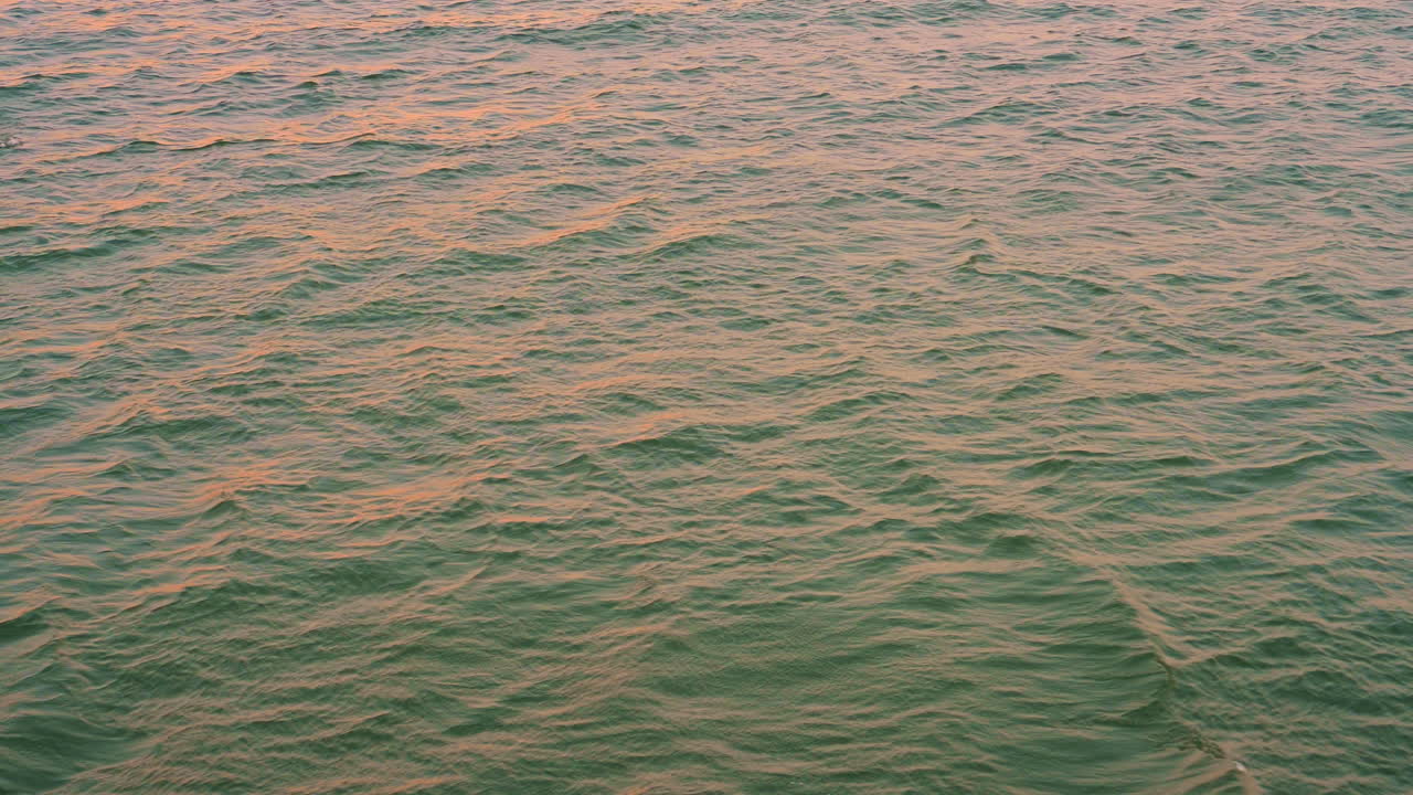 reflejo colorido de la puesta de sol dorada sobre la ola de agua de mar moviéndose para el fondo