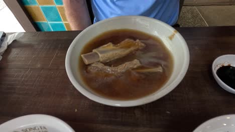 person eating soup with meat and vegetables.