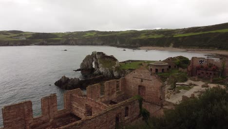 vista aérea inversa descendiendo a través de traeth porth wen beach bay fábrica de ladrillos abandonada en la costa del mar irlandés