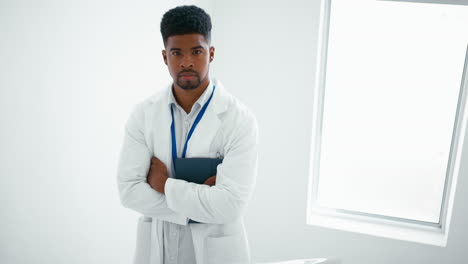portrait of serious male doctor wearing white coat holding digital tablet on stairs in hospital